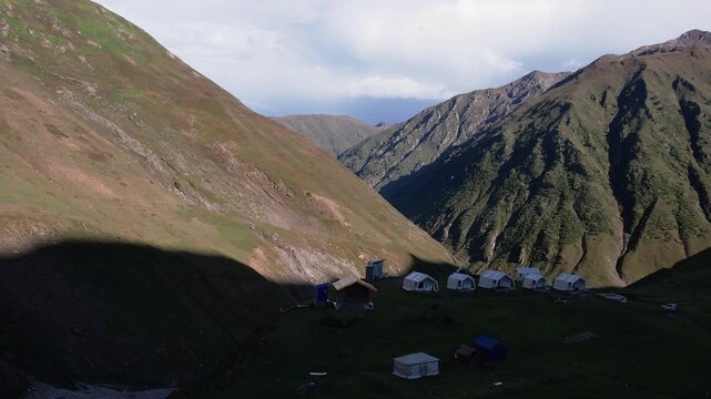 Tents set up on a grassy slope below steep mountains near Noori Top in Neelum Valley. Sharda, Kashmir