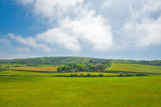 Beautiful panoramic landscape view of english rural countryside scenery showing farmland and rolling hills with cloudy blue sky background