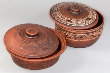 Clay pot and roaster with shifted lids on gray background
