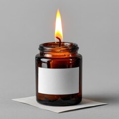 Burning scented candle in glass jar on a grey background