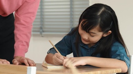 Asian girl writing or taking a note while teacher checking classwork. Caucasian teacher help happy student doing test or classwork while diverse student study in science lesson. Education. Pedagogy.