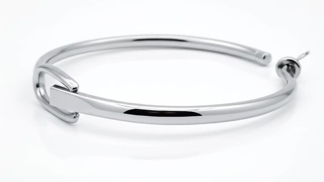 Elegant Silver Bangle Bracelet With Interlocking Clasp Against A Clean White Background
