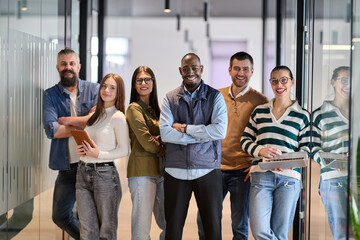 Fototapeta premium Group of confident professionals walking together through a bright modern office corridor. Concept of teamwork, diversity, success, collaboration, and positive workplace culture.