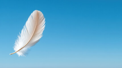 Naklejka premium White feather floats gracefully in clear blue sky, symbolizing purity and lightness