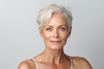 Portrait of a beautiful senior woman with gray hair smiling on gray background
