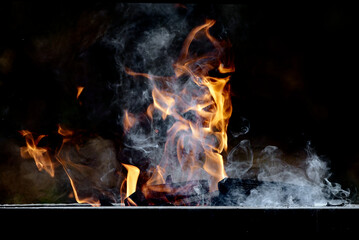 Blaze flames background. Flame of fire. White smoke above dark logs.
