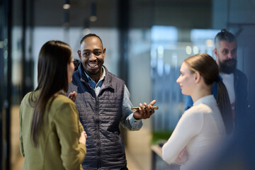 Group of diverse coworkers having a cheerful conversation in a modern office, representing teamwork, communication, leadership, and collaboration in a professional business environment.
