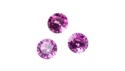 Three round-cut pink sapphires sit clustered on a stark black background, showcasing their facets and bright color