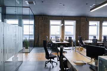 Contemporary open space office interior with minimalist design, black chairs, wooden desks, and glass partitions, representing a professional corporate workspace environment.