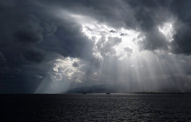 Sunlight breaking through the clouds, seen from the ferry between Calabria and Sicily in Italy