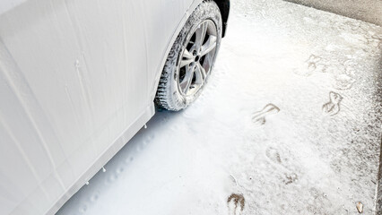 Powdered footprints echo in fresh snow beside a parked car, evoking Yule's mysteries and Imbolc's quiet promise