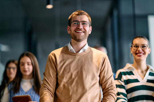 Group of young business team walking together through a modern office hallway, smiling and discussing work. Concept of confidence, teamwork, leadership, and positive workplace culture. - Powered by Adobe
