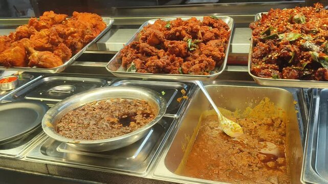 Different variety of spicey meat dish or cuisine on traditional indian non-vegetarian fast food local shop display trays. Closeup of unhealthy asian street food selling on restaurant or food court.