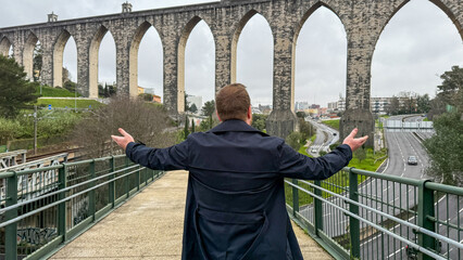 A contemplative Caucasian man embraces ancient aqueduct vistas, conjuring medieval engineering...