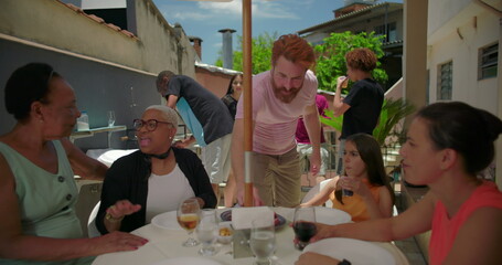 Family chatting and laughing during outdoor lunch, diverse group sharing stories and creating...