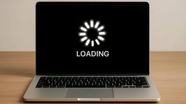 Laptop computer displaying loading screen on wooden table  