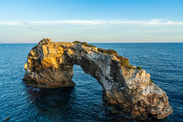 Scenic view of natural stone arch in the turquoise sea at Cala Santanyi, Mallorca, Spain. Dramatic Mediterranean coastline with clear water and rugged cliffs.