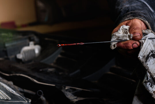 Car mechanic checking the motor oil level on the dipstick.