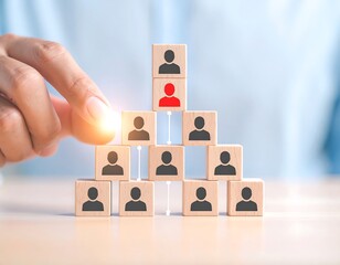 Hand arranging wooden blocks with people icons, forming a pyramid structure