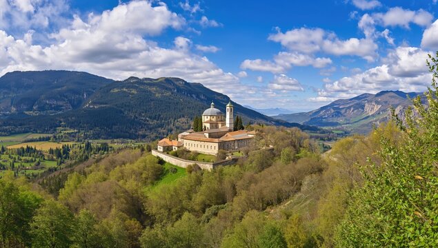 Wide-angle perspective of an ancient religious cloister surrounded by forest and mountains in spring