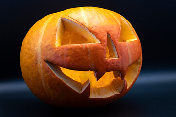 A pumpkin with a scary face carved is close-up. The symbol of Halloween