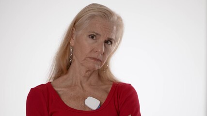 Concerned happy mature woman wears a heart sensor on her chest to track atrial fibrillation, promoting health and wellness while exercising. Focused on living healthily.