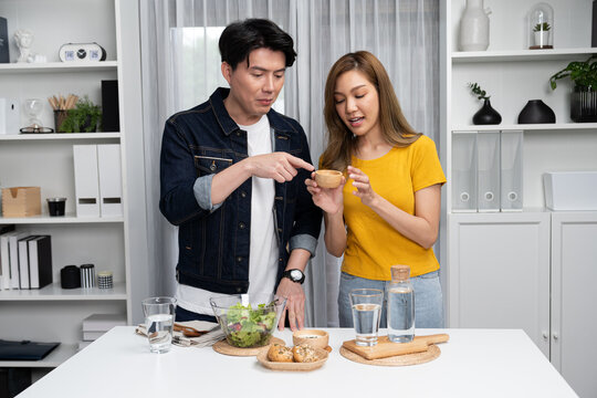 Cooking show on live streaming with two chef influencers teaching mixed salad with dressing for easy special menu at home. Ingredients placing on table with bread bun wholegrain side dish. Infobahn.