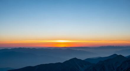 Obraz premium Calm dawn light over distant mountain range and misty valley