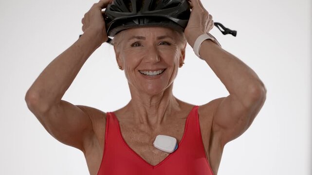Happy mature woman models a heart sensor designed for monitoring atrial fibrillation. She showcases her healthy lifestyle with joy and confidence.