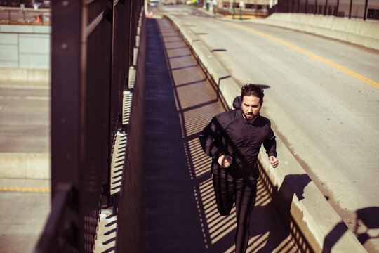 Young adult man jogging on a bridge