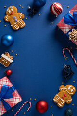 A vertical holiday scene featuring gingerbread men, wrapped gifts, shiny ornaments, and candy canes...