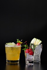 A close-up shot of three uniquely crafted cocktails on a dark background. Each drink is carefully garnished, presenting a vibrant and appetizing appeal.