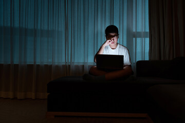 Teenage boy using laptop at night