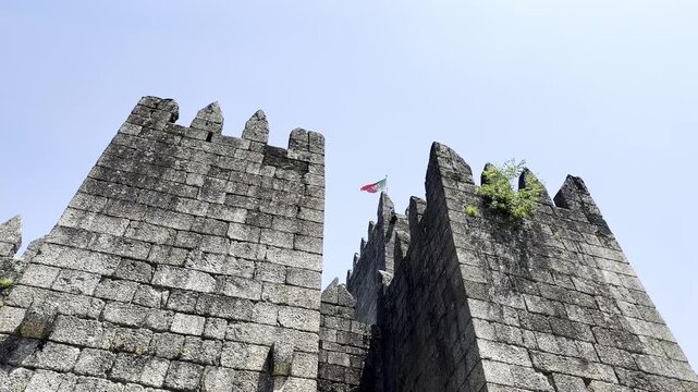 Medieval castle walls rise against the clear sky in Guimaraes, Portugal. The ancient stone fortress,
