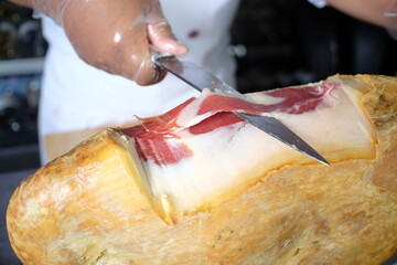 Expert hand carving a delectable slice of ham with a sharp knife