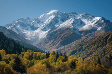 Naklejka premium Snow-capped peaks above a valley of autumn trees, crystal clear sky, vivid yet natural color grading.