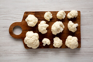 White Organic Raw Cauliflower Florets on a Wooden Board, top view.