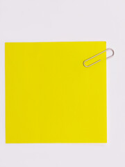 Blank yellow note with a paperclip on a white background