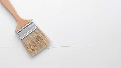 Paintbrush loaded with paint resting on a white coated floor surface. Getting walls and floors ready for a fresh coat of paint. Blank area for text, design, home interior, wall, white, poster concept.