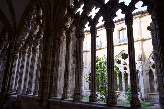 Symmetrical medieval cloister courtyard with gothic arches and well kept garden, historic European architecture under soft natural daylight