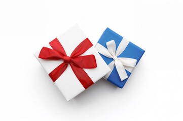 Red ribbon adorned white present box and blue present box with white ribbon on white backdrop. Overhead perspective.