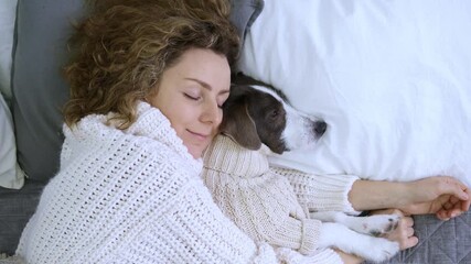 Woman and pet sleep in embrace on bed, dressed in cozy sweaters. Gentle hugs owner and pet create atmosphere warmth and love. Touching moment unity between person and pet, demonstrating special bond.