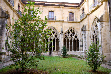 Fototapeta premium Medieval cloister garden with gothic arches and lush greenery in peaceful courtyard