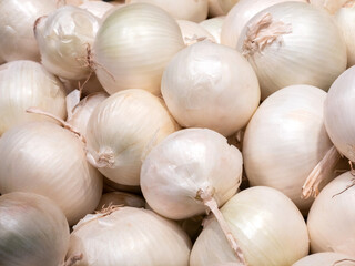 A fresh pile of whole white onions at a market
