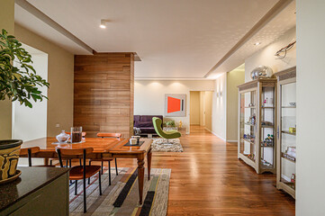 An inviting living space showcases a blend of textures and materials with warm wood flooring and a stylish dining set. A green accent chair adds a pop of color to the neutral palette