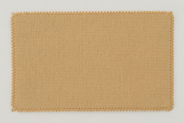 A rectangular piece of burlap fabric with a zigzag stitched edge isolated on white