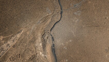Aerial perspective of a narrow water flow in a parched lakebed