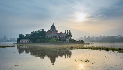Obraz premium Monastery at misty sunrise over water with summer sky and architecture