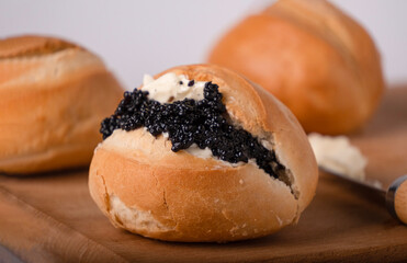 one round wheat bun with butter and black caviar, close-up
