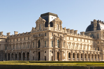 Obraz premium Elegant facade of the Louvre Palace in Paris under clear blue sky. Historic architecture representing French art, culture, and heritage in a world-famous landmark.